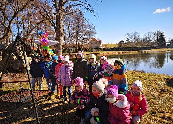 Dzieci z oddziałów przeszkolnych 5 i 6 -latków nad jeziorem w Redkowicach. Jedno z dzieci trzyma Marzannę.