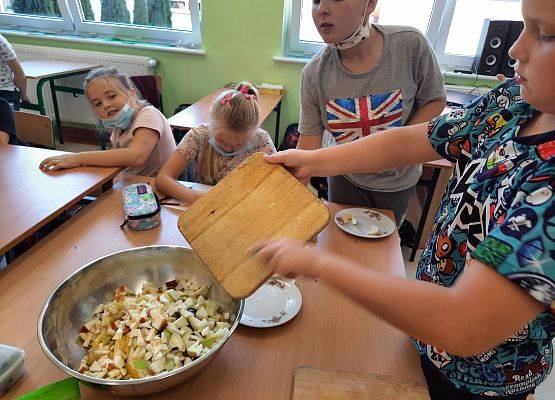 Uczeń wrzuca do miski pokrojone owoce