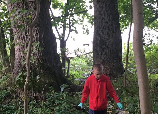 Uczeń w lesie podczas sprzątania świata.