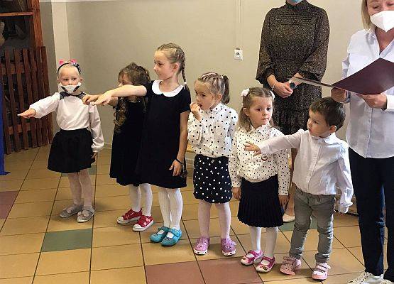Dzieci z oddziału 5-latków z wyciągniętymi rękoma ślubują na sztandar szkoły