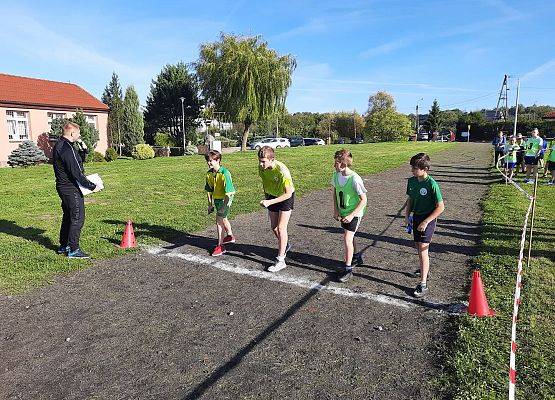 Sztafetowe biegi przełajowe chłopców. Czterech chłopców stoi na starcie. Przygotowują się do rozpoczecia biegu.