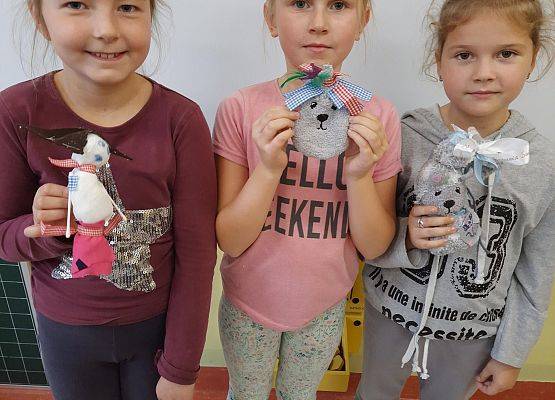 Trzy dziewczynki trzymają w dłoni laleczki zrobione ze skarpetek na języku kaszubskim