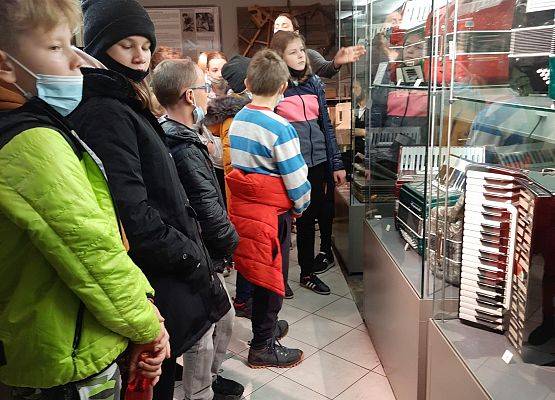 Uczniowie w Muzeum Akordeonu. Dzieci oglądają eksponaty za szybą