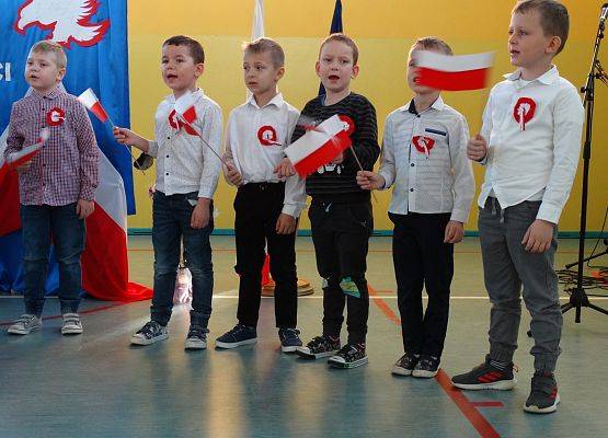 Sześcioro chłopców śpiewa piosenkę. W dłoniach trzymają flagi Polski.