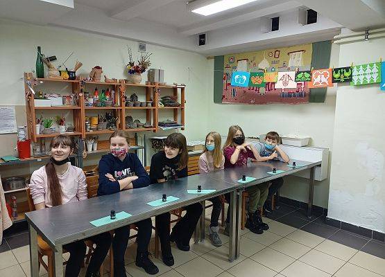 Uczniowie siedzą przy metalowych stołach . Przygotowują się do warsztatów
