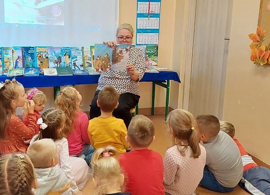 Bibliotekarka pokazuje przedszkolakom obrazki do fragmentu książki