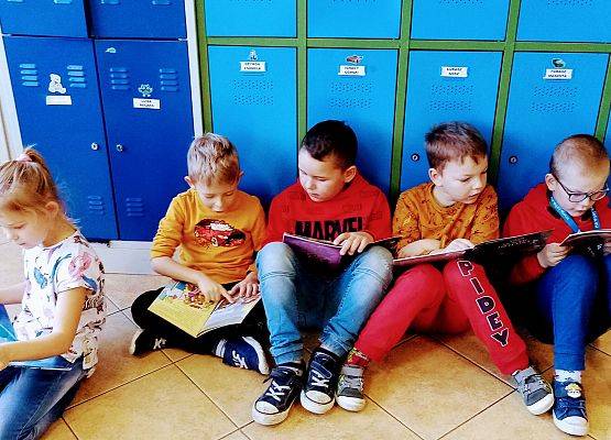 Pięcioro uczniów siedzi na podłodze i czyta książki