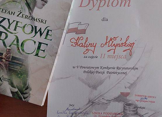 Dyplom dla Kaliny Młyńskiej za zajęcie 2 miejsca w V Powiatowym Konkursie Recytatorskim Polskiej Poezji Patriotycznej oraz książka pod tytułem "Syzyfowe Prace"