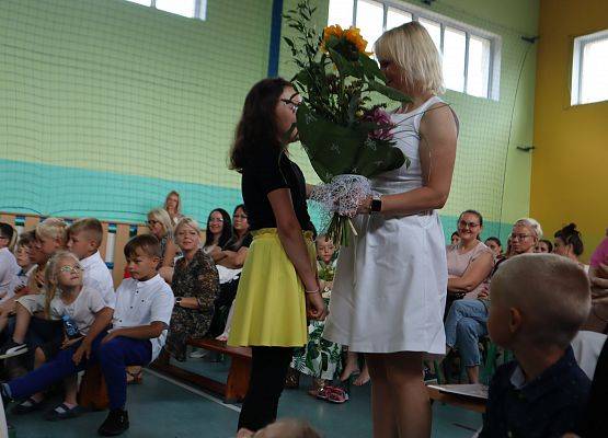 Zakończenie roku szkolnego 6-latków i uczniów z klasy trzeciej- uczennica wręcza kwiaty pani dyrektor.