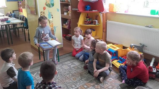  Grafika #2: Uczniowie klasy II SP czytają dzieciom z oddziału przedszkolnego.