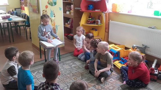  Grafika #3: Uczniowie klasy II SP czytają dzieciom z oddziału przedszkolnego.