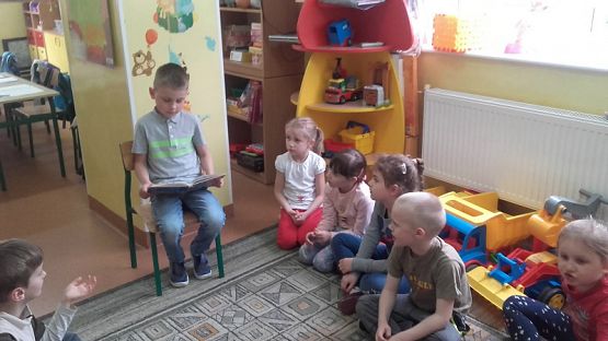  Grafika #5: Uczniowie klasy II SP czytają dzieciom z oddziału przedszkolnego.