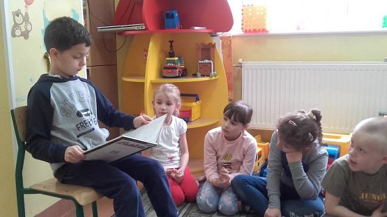  Grafika #8: Uczniowie klasy II SP czytają dzieciom z oddziału przedszkolnego.